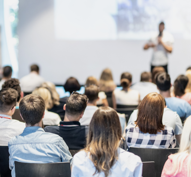 Участники курсов слушают лектора на сцене